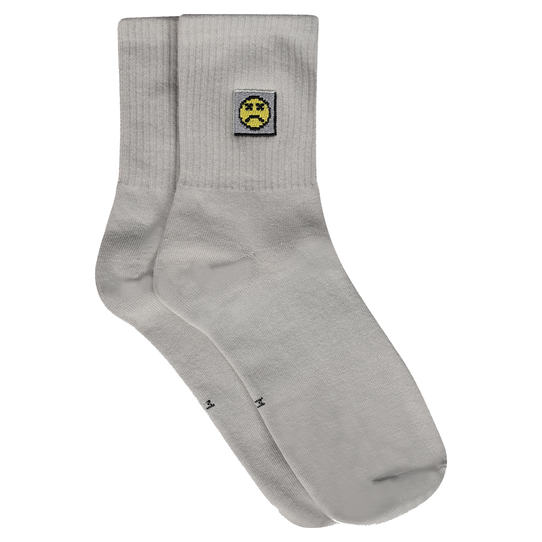 Photograph of grey socks with sad face embroidery design