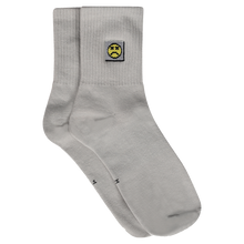 Load image into Gallery viewer, Photograph of grey socks with sad face embroidery design
