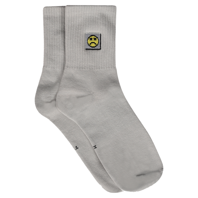 Photograph of grey socks with sad face embroidery design