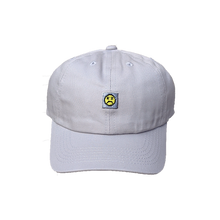 Load image into Gallery viewer, Photograph of grey minesweeper cap with embroidered sad face design
